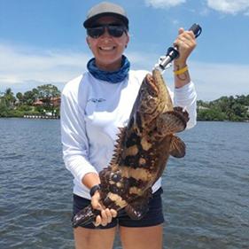 woman holding a fish with ocean in background